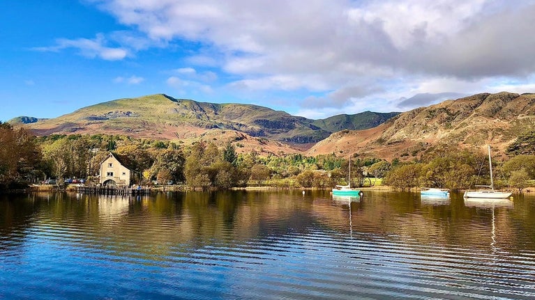 An autumnal scene showing Pier cottage, the lake and sailing boats